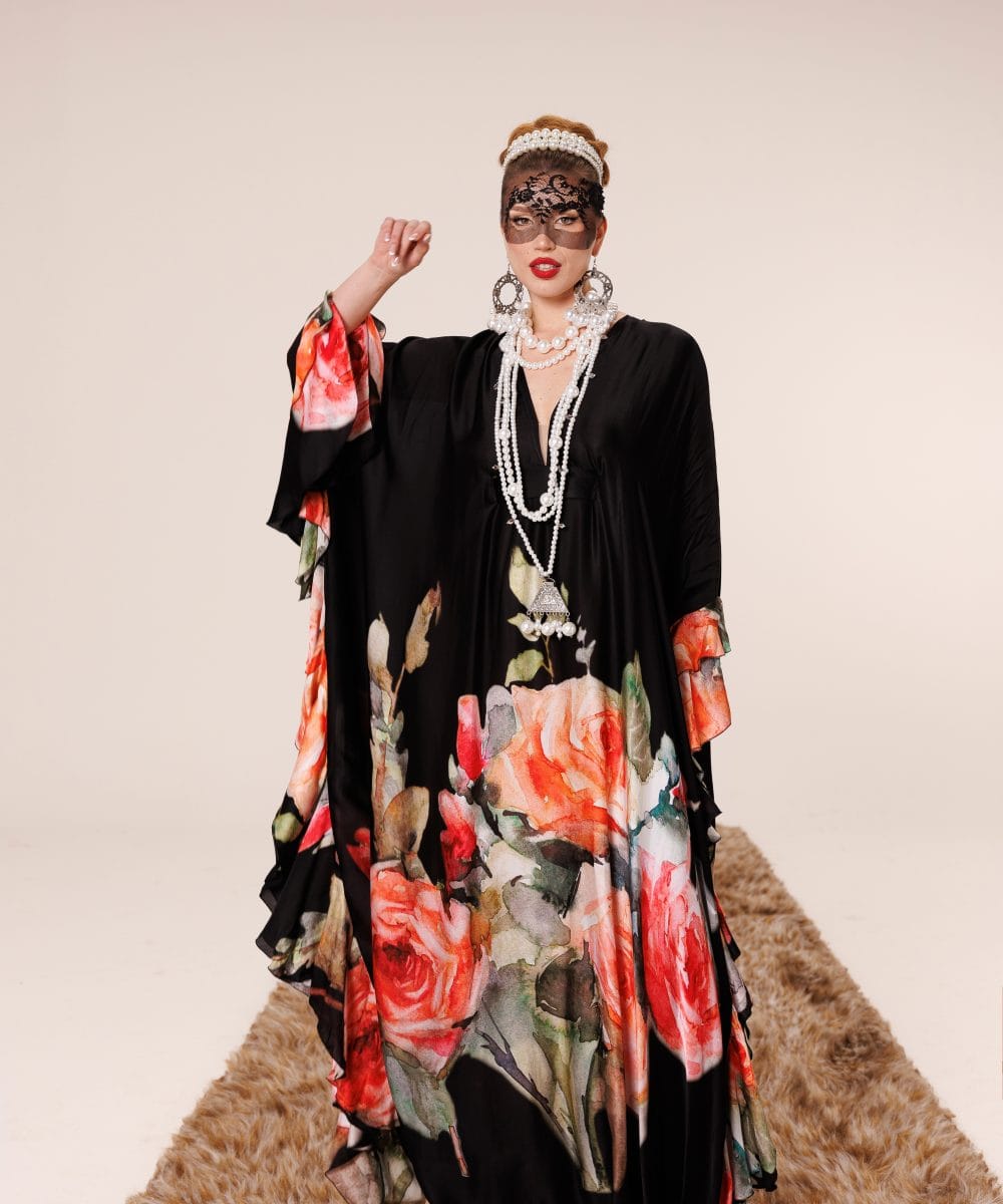 Derin V dekolteli, zarif inci kolyeler ve siyah dantel maske ile kombinlenmiş, kırmızı gül desenli %100 saf dut ipeği Soul of Leila tasarım elbisenin pelerinli asil duruşu.