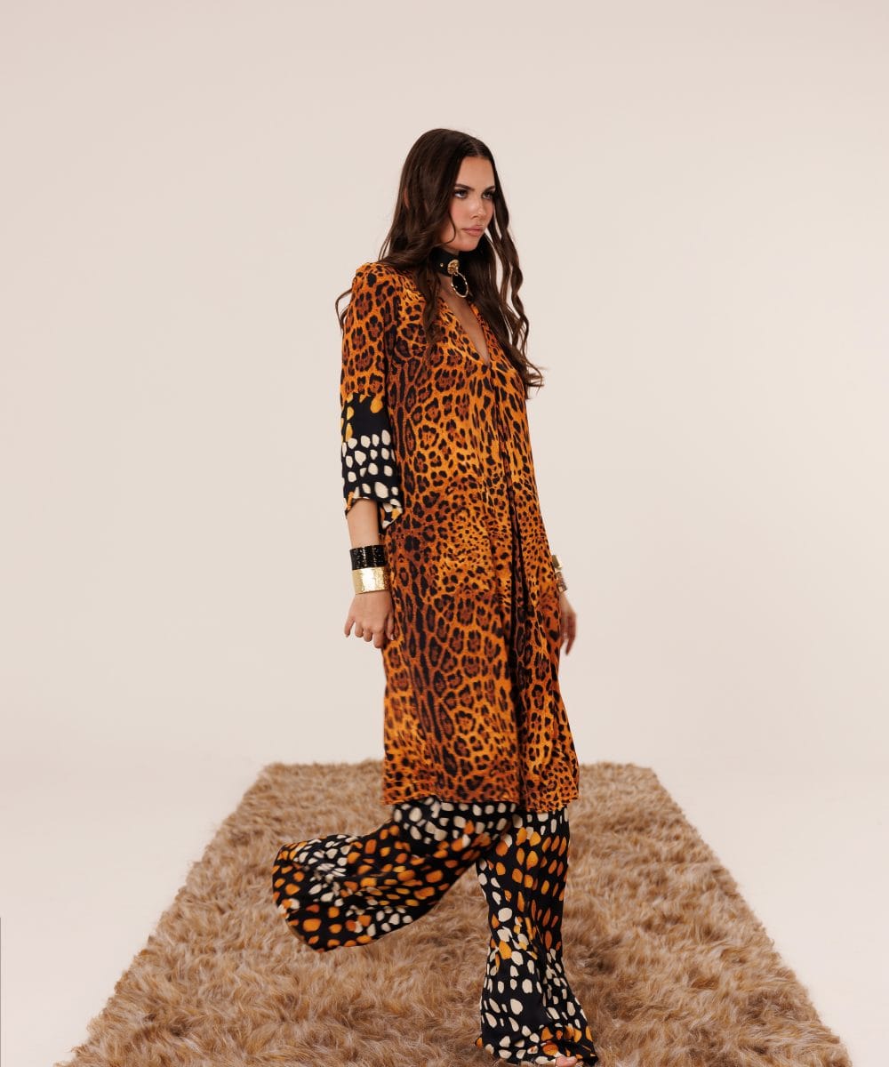 Soul of Leila kadınının cesur duruşunu sergileyen, yürüyüş esnasında ipek kumaşın akışkanlığını vurgulayan leopar ve soyut desenli lüks takım yandan görünüm.